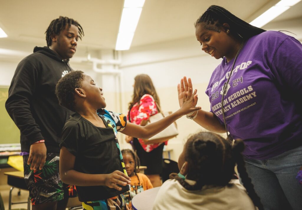 A young student gives a high five to a Freedom Schools Literacy Academy apprentice